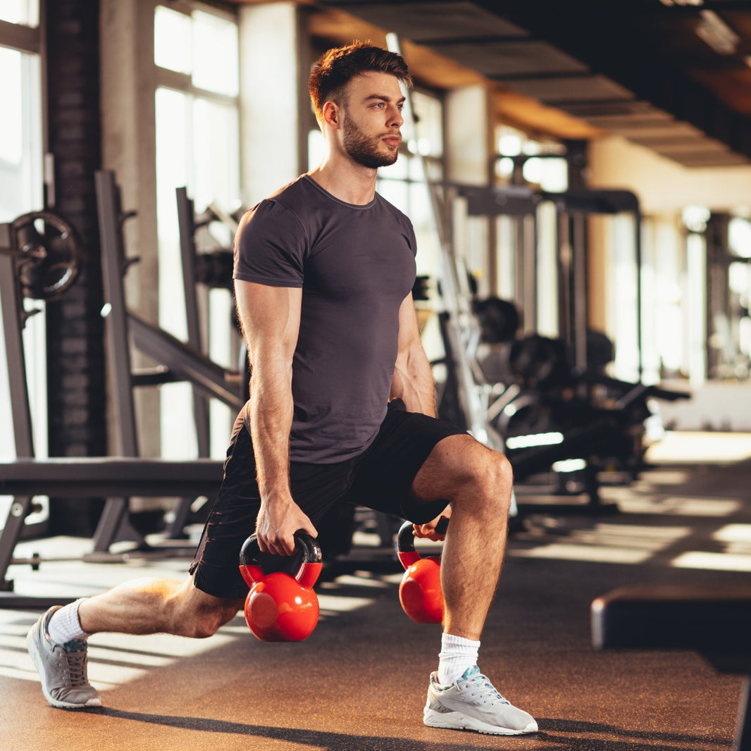Man exercising with kettlebells in a gym setting