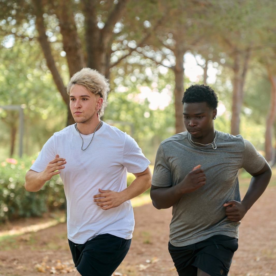 Two individuals running outdoors on a path with trees in the background