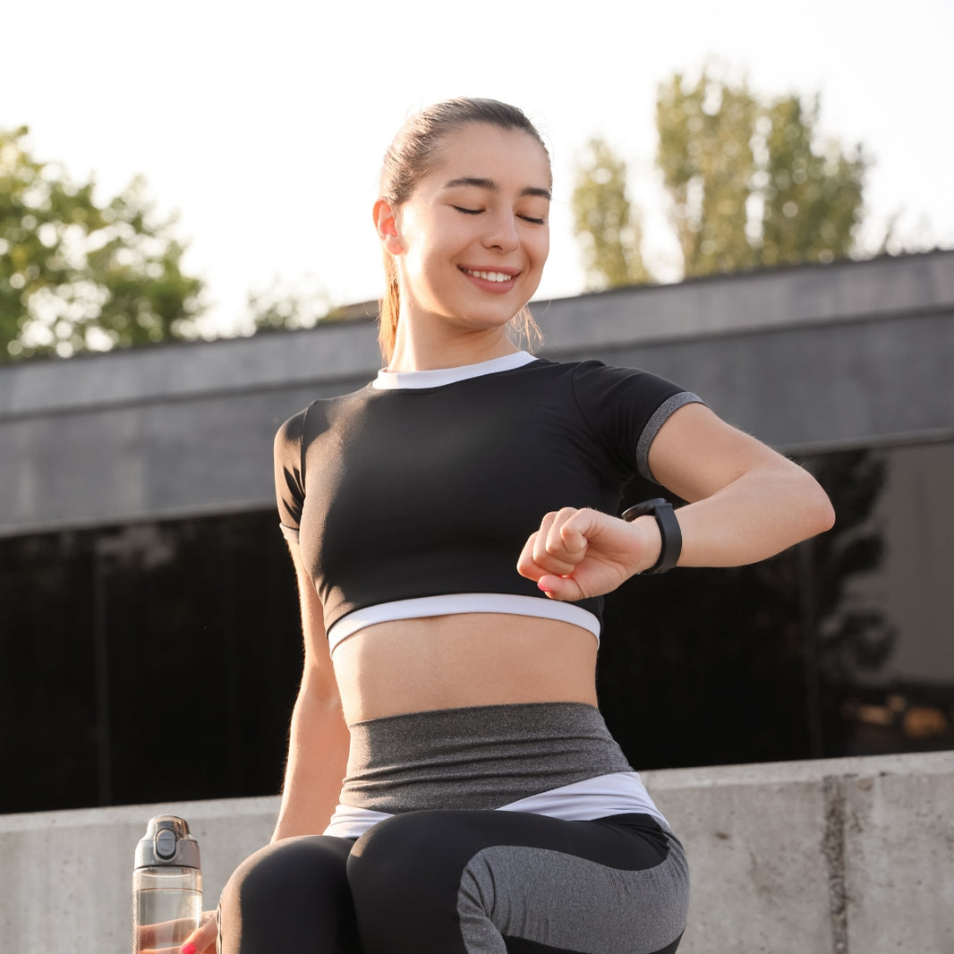 Woman in athletic wear checking her watch outdoors
