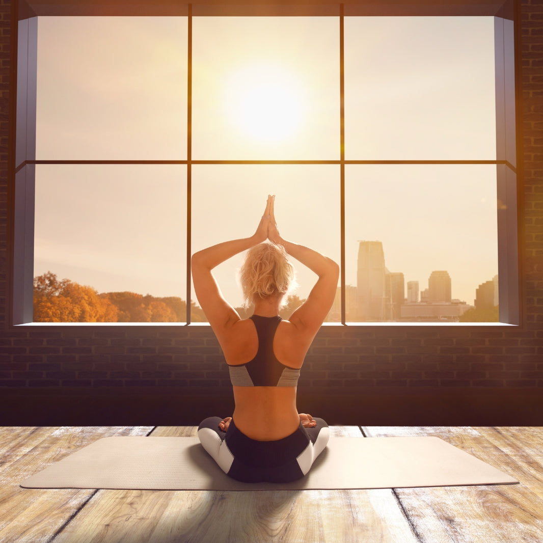 Person practicing yoga in front of a large window with a cityscape view